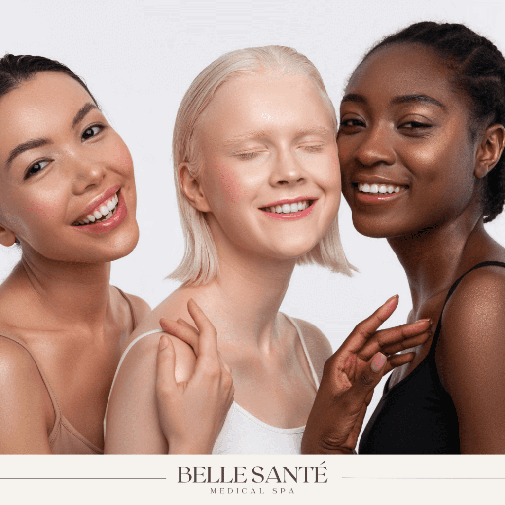 Three young women of different skin tones smiling.