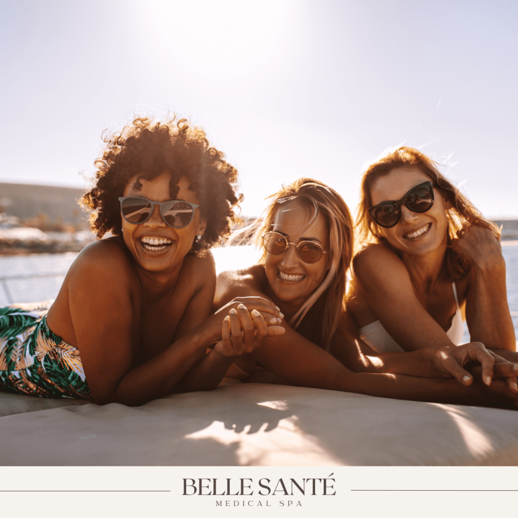 Three young women of different races laying on a beach in the sun.