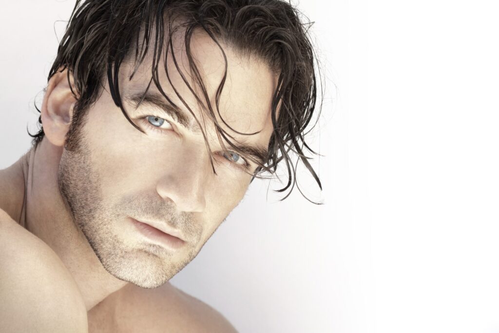 Handsome man with a serious look on his face staring at the camera with hair draping down